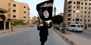 أحد أعضاء التابعين لداعش يرفع علمها في مدينة الرقة - رويترز